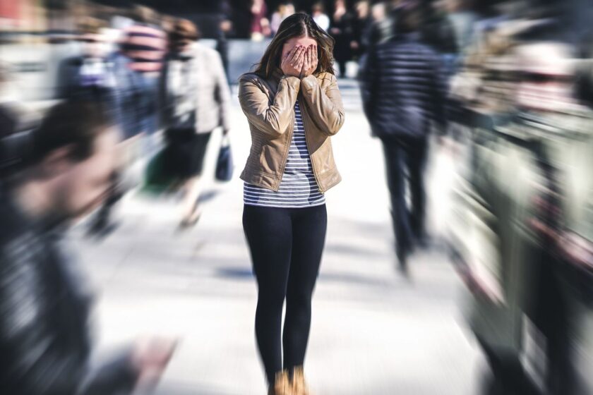woman standing in a crowd with blurred people - schizophrenia vs schizotypal