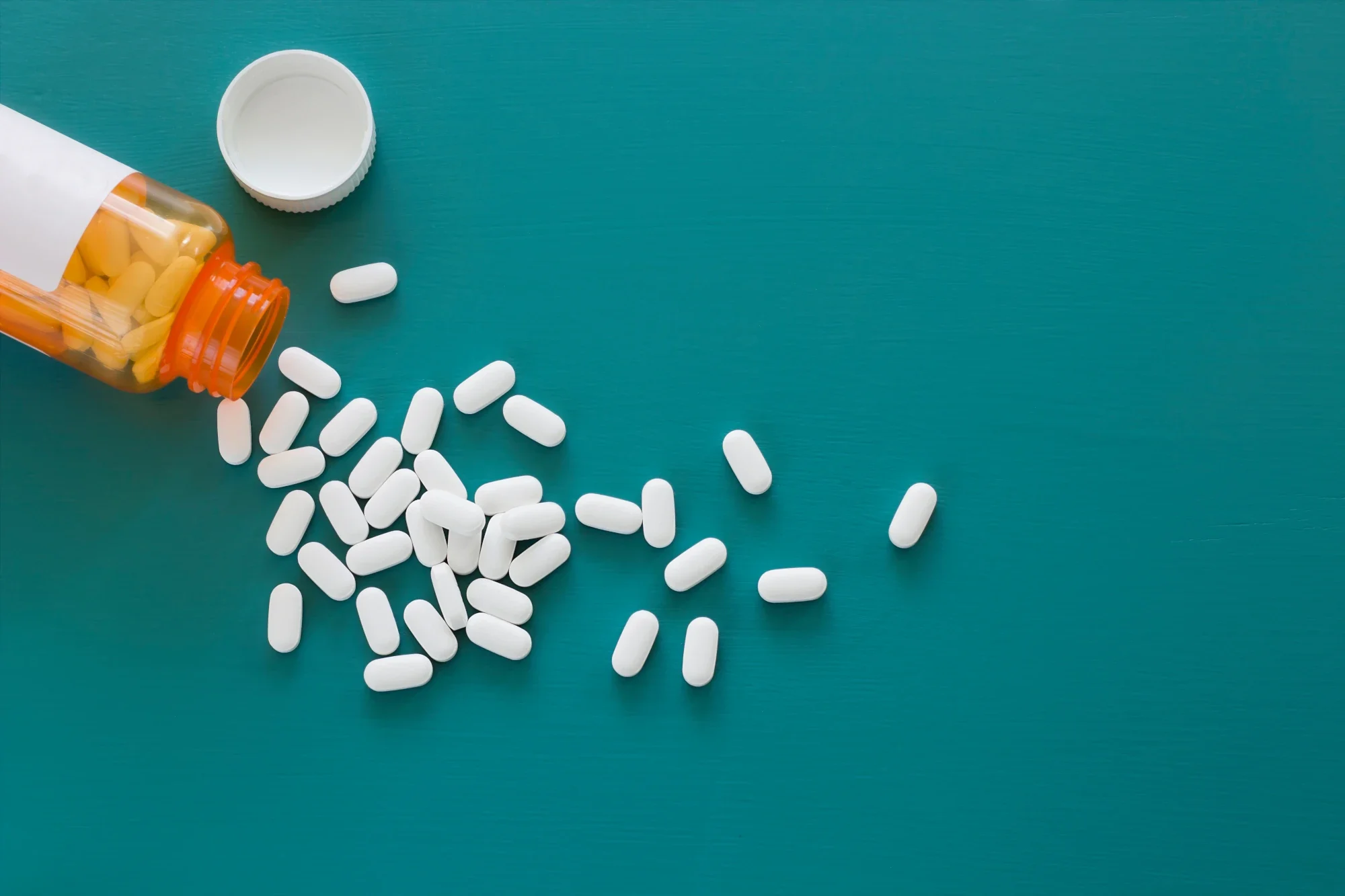Olanzapine prescription bottle and tablets on a table.