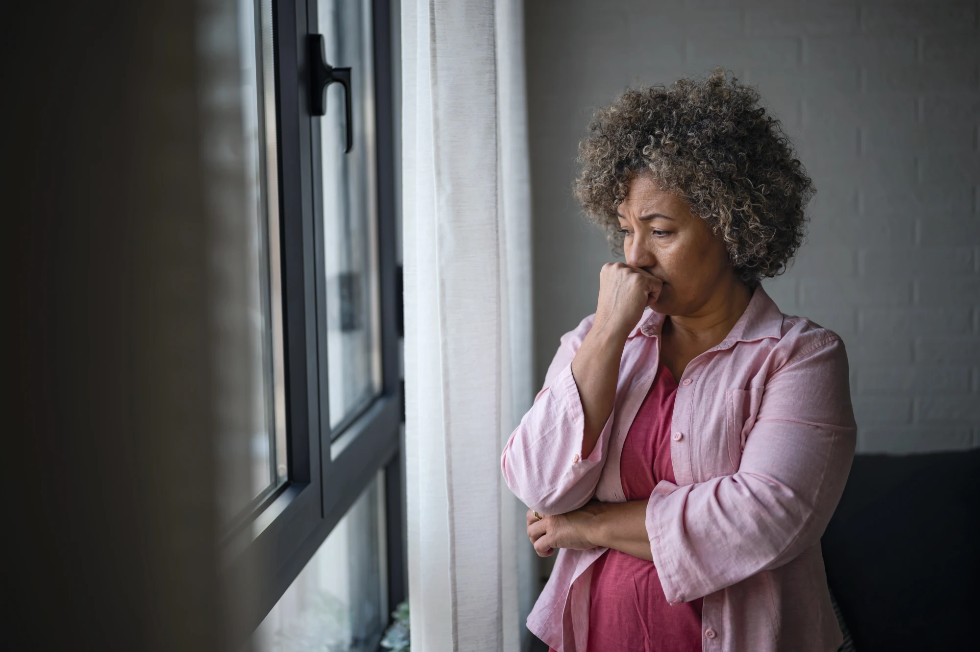 Woman sitting by a window at home, looking outside