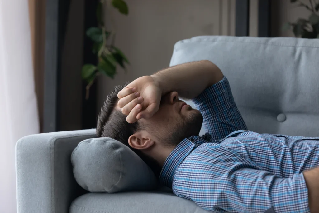 Man lying back on a couch at home with his eyes closed